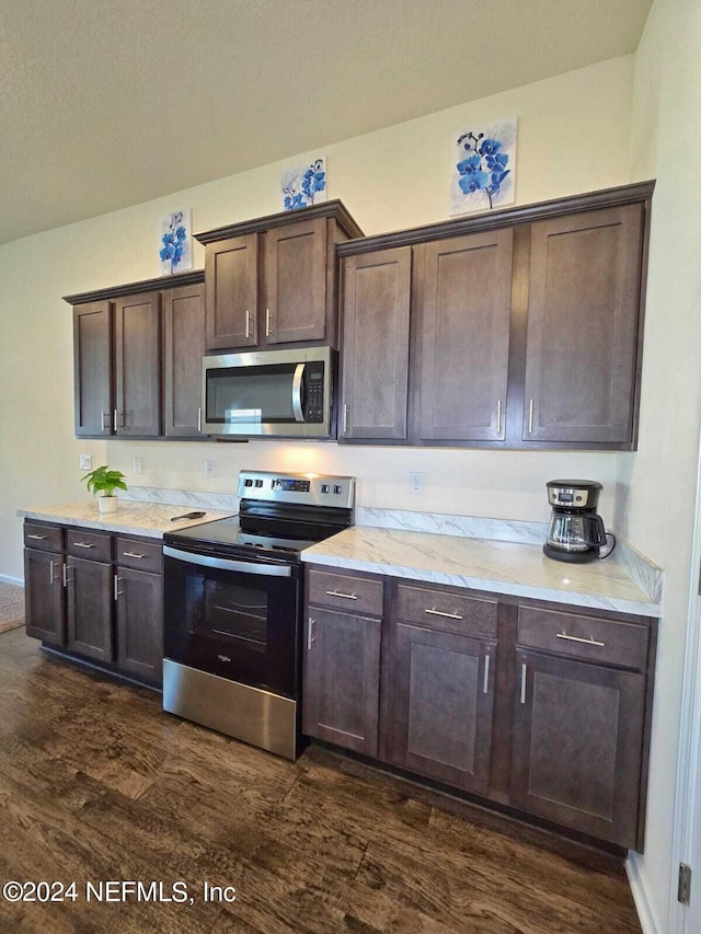 kitchen featuring dark brown cabinets, light stone countertops, stainless steel appliances, and dark hardwood / wood-style floors