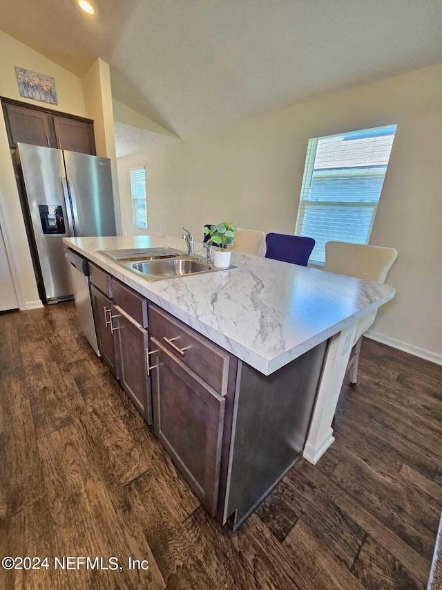 kitchen featuring a kitchen island with sink, stainless steel appliances, vaulted ceiling, dark brown cabinetry, and dark hardwood / wood-style flooring