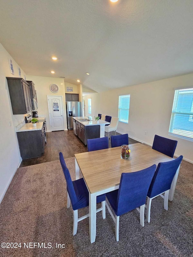 dining space with sink, dark wood-type flooring, and vaulted ceiling