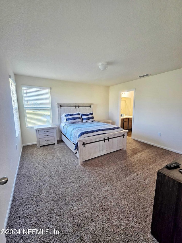 bedroom featuring connected bathroom, a textured ceiling, and carpet floors