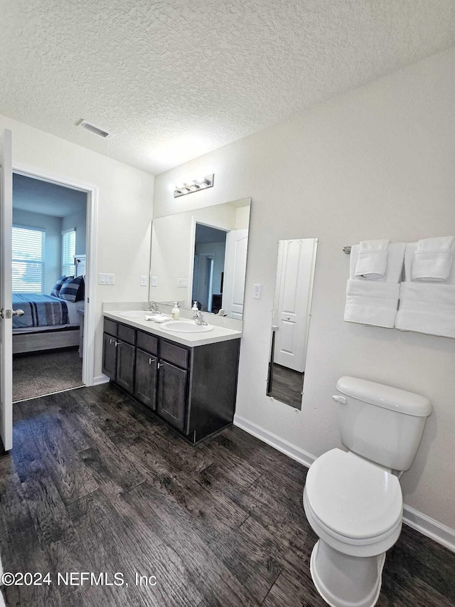 bathroom with vanity, toilet, hardwood / wood-style flooring, and a textured ceiling