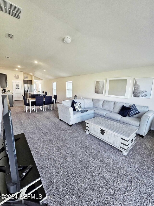 carpeted living room featuring a textured ceiling and lofted ceiling