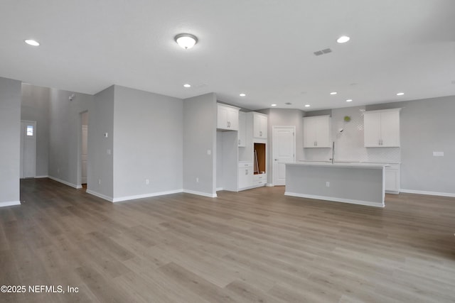 unfurnished living room featuring light wood-type flooring, baseboards, and recessed lighting