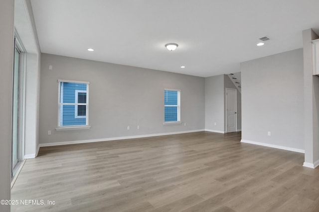 empty room featuring light wood finished floors, recessed lighting, visible vents, and baseboards