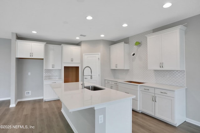 kitchen featuring sink, an island with sink, decorative backsplash, white cabinets, and light wood-type flooring