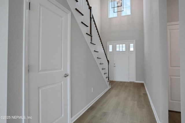 foyer with light wood-style floors, plenty of natural light, stairs, and baseboards