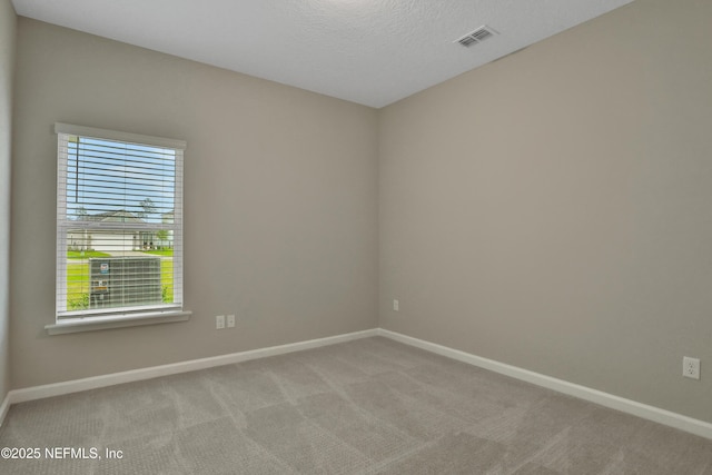 carpeted spare room with baseboards, visible vents, and a textured ceiling