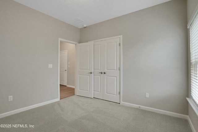 unfurnished bedroom with a closet, carpet flooring, and baseboards