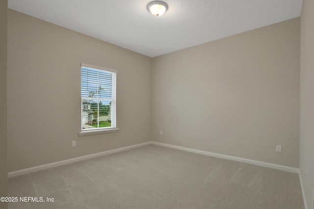 carpeted spare room featuring a textured ceiling and baseboards