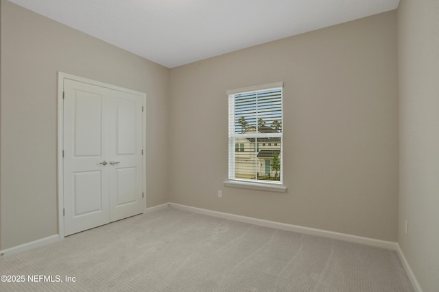 unfurnished room featuring light carpet and baseboards