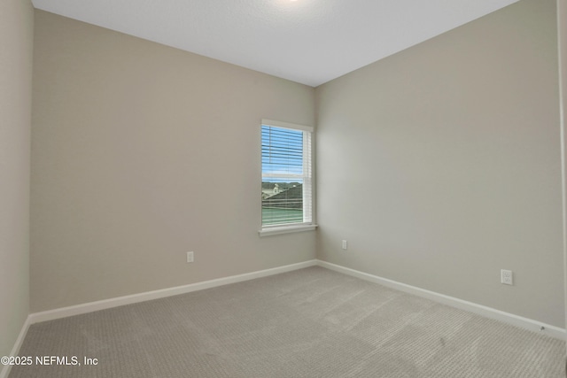 spare room with light carpet and baseboards