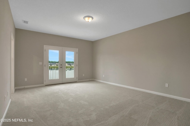 spare room featuring baseboards, visible vents, french doors, a textured ceiling, and carpet flooring