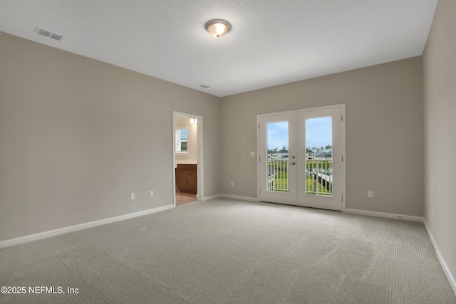 empty room with french doors, light colored carpet, visible vents, and baseboards