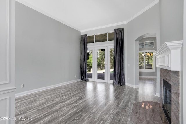 unfurnished living room with ornamental molding, hardwood / wood-style floors, a fireplace, and a chandelier