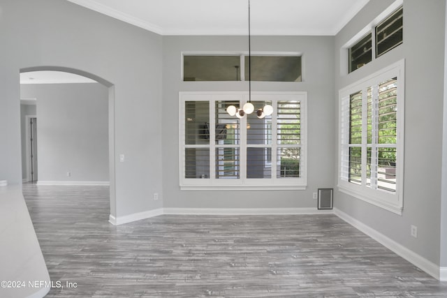 unfurnished dining area with a notable chandelier, ornamental molding, and hardwood / wood-style floors