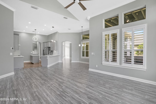 unfurnished living room featuring ornamental molding, dark hardwood / wood-style floors, high vaulted ceiling, and ceiling fan