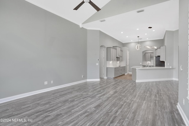 unfurnished living room with crown molding, wood-type flooring, sink, and ceiling fan