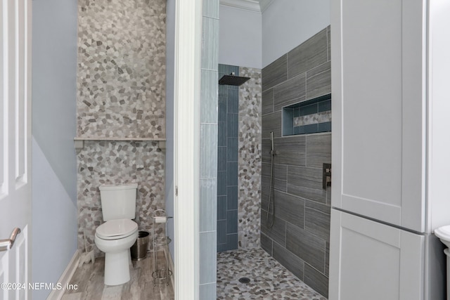 bathroom with a tile shower, hardwood / wood-style flooring, and toilet