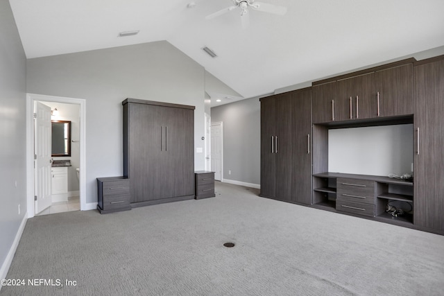 unfurnished bedroom featuring lofted ceiling, light colored carpet, connected bathroom, and ceiling fan