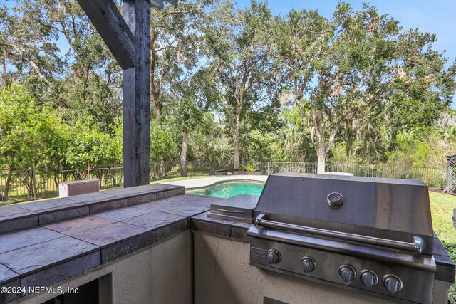 view of patio with a fenced in pool and a grill