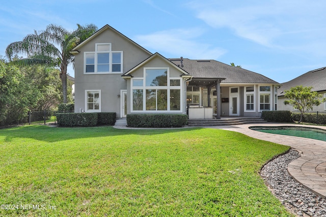 rear view of house with a patio, a fenced in pool, and a yard