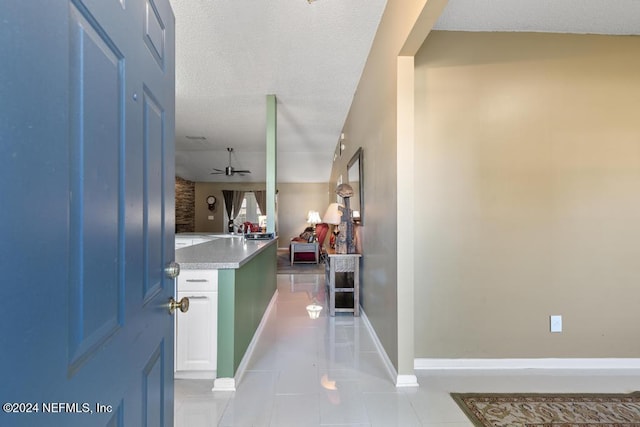 hallway with a textured ceiling and light tile patterned floors