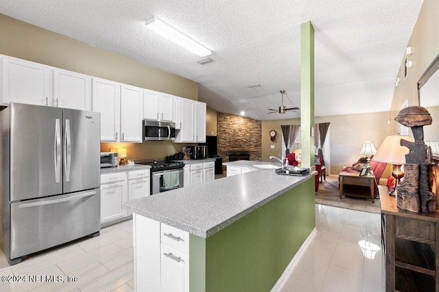 kitchen featuring an island with sink, ceiling fan, a textured ceiling, white cabinetry, and stainless steel appliances