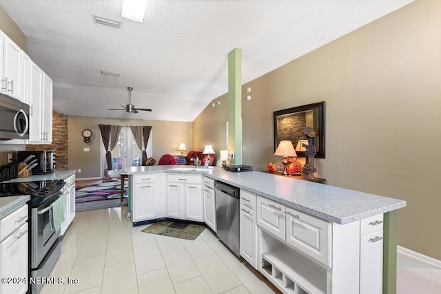 kitchen with appliances with stainless steel finishes, kitchen peninsula, ceiling fan, lofted ceiling, and white cabinets