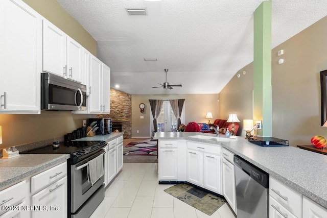 kitchen with kitchen peninsula, white cabinets, ceiling fan, sink, and stainless steel appliances