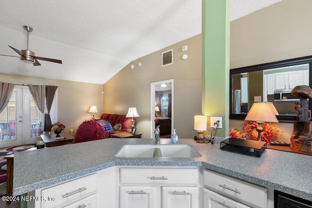 kitchen with sink, kitchen peninsula, white cabinetry, ceiling fan, and vaulted ceiling