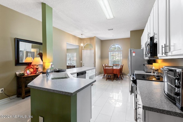 kitchen featuring appliances with stainless steel finishes, decorative light fixtures, a textured ceiling, and white cabinetry