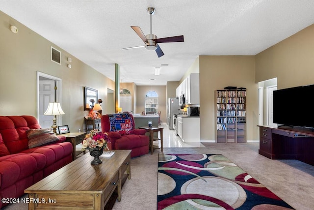 living room with light carpet, a textured ceiling, and ceiling fan