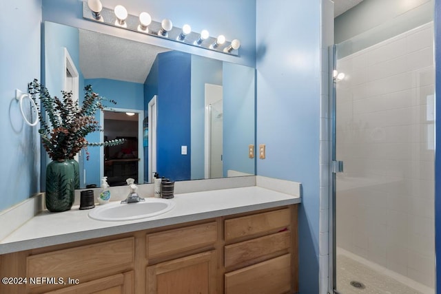 bathroom featuring vanity, a textured ceiling, and an enclosed shower