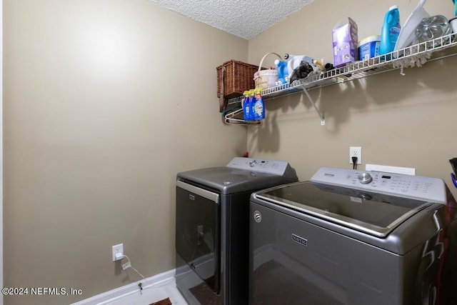 clothes washing area with washer and clothes dryer and a textured ceiling