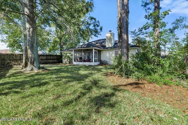 4021 Savannah Glen Blvd, Orange Park, FL 32073 - rear view of house featuring stucco siding, a fenced backyard, a chimney, a lawn, and a sunroom