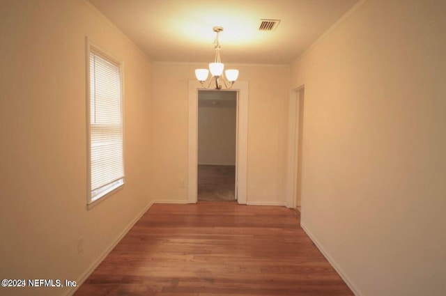 unfurnished dining area with hardwood / wood-style flooring, ornamental molding, a chandelier, and plenty of natural light