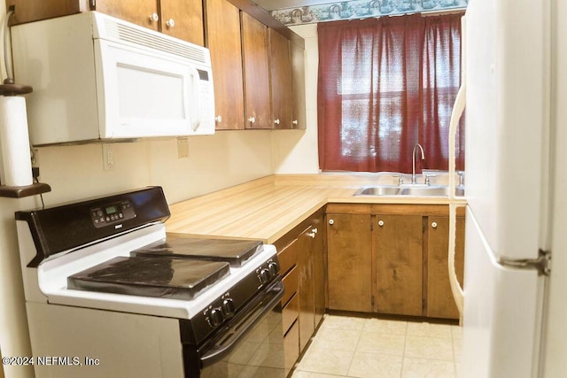 762 N Walnut St, Starke, FL 32091 - kitchen featuring white appliances, a sink, light countertops, brown cabinets, and light tile patterned flooring