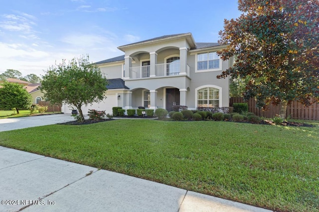 view of front of home with a balcony and a front lawn