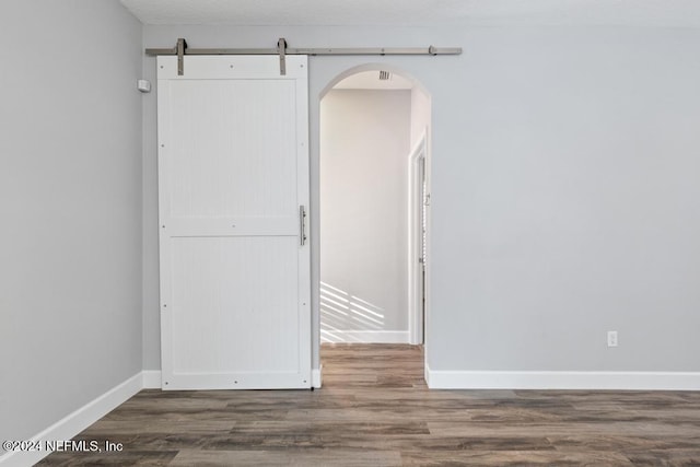 unfurnished room featuring a barn door and dark hardwood / wood-style floors