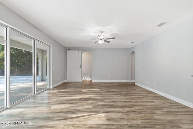 unfurnished room featuring a barn door, ceiling fan, and wood-type flooring