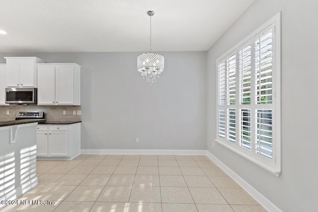 kitchen with white cabinets, appliances with stainless steel finishes, a wealth of natural light, and a notable chandelier