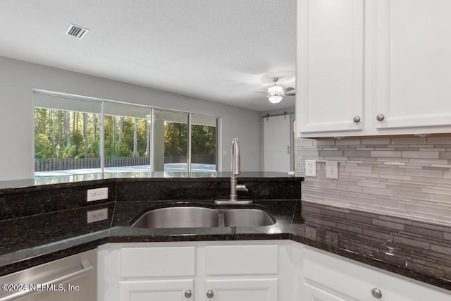 kitchen featuring dark stone countertops, sink, white cabinets, and stainless steel dishwasher