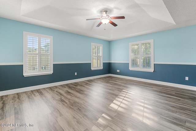 unfurnished room with a raised ceiling, ceiling fan, a textured ceiling, and hardwood / wood-style flooring