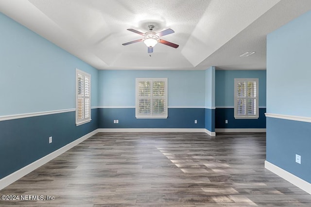 unfurnished room with a textured ceiling, ceiling fan, and dark wood-type flooring