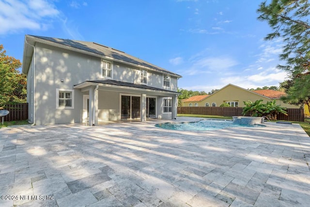 rear view of property with a patio area, pool water feature, and a pool with hot tub