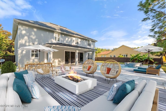 rear view of property featuring pool water feature, a patio area, a fenced in pool, and an outdoor living space with a fire pit