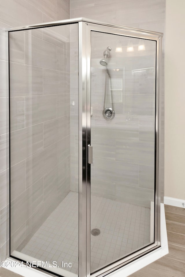 bathroom with a shower with door and wood-type flooring