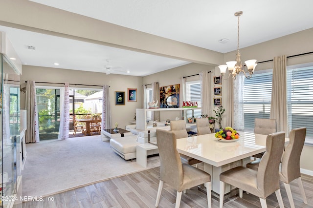 dining space featuring ceiling fan with notable chandelier and light wood-type flooring