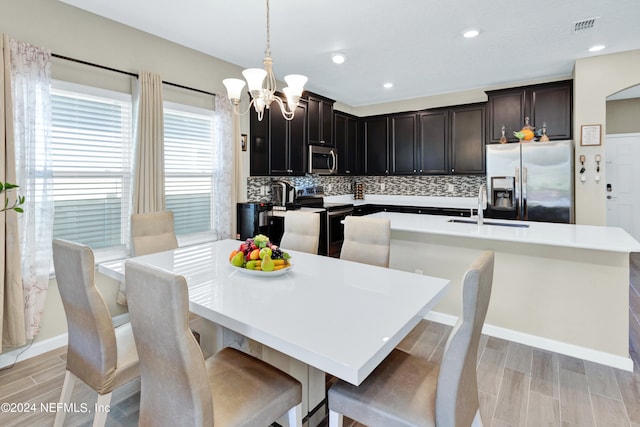 dining room with an inviting chandelier, sink, and light wood-type flooring