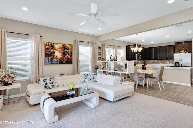 carpeted living room with ceiling fan with notable chandelier